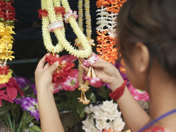 Kvinna som tittar på konstgjorda blommor halsband — Stockfoto