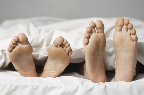 Barefoot casal deitado na cama — Fotografia de Stock