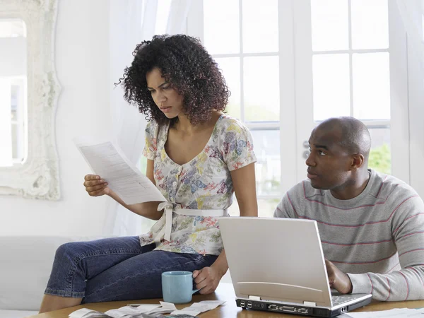 Couple utilisant un ordinateur portable et un document de lecture — Photo