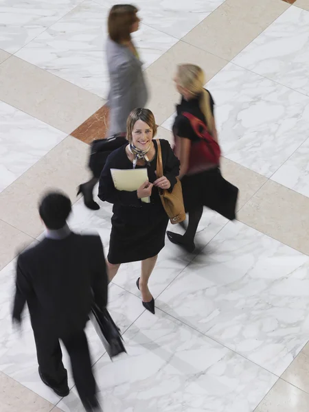 Mujer de negocios de pie entre personas — Foto de Stock