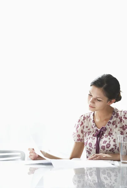 Jovem mulher sentada à mesa — Fotografia de Stock