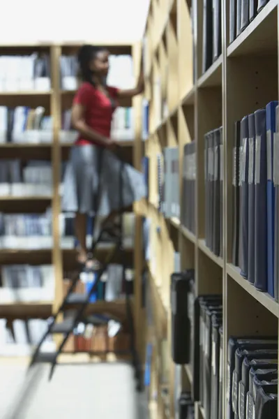 Office worker on ladder in file storage room — Stock Photo, Image