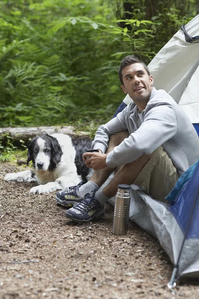 Çadır tarafından oturan köpekli adam — Stok fotoğraf
