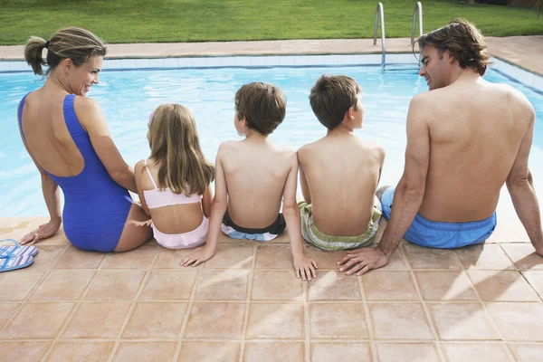 Familie zitten bij zwembad — Stockfoto