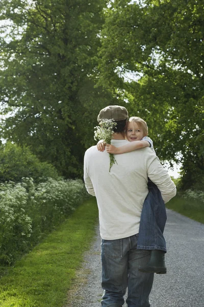 Padre che porta figlia con fiori di campo — Foto Stock