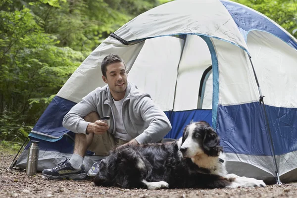 Çadır tarafından oturan köpekli adam — Stok fotoğraf