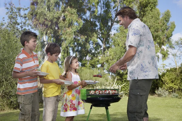 Father serving grilled food — Stock Photo, Image