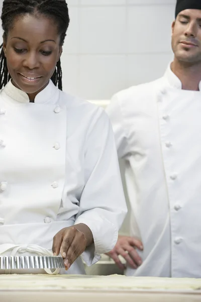 Chef watching female preparing food — Stock Photo, Image