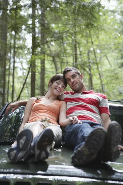 Couple assis sur le capot de voiture — Photo