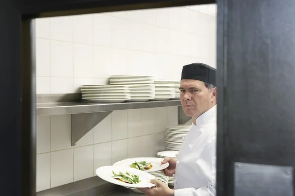 Человек с тарелками на кухне — стоковое фото