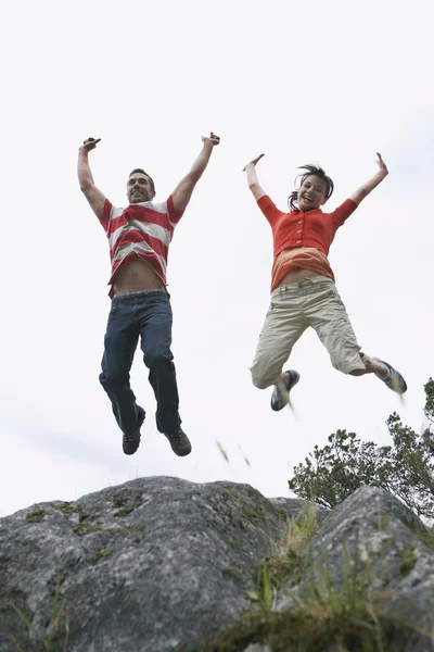 Couple leaping with arms raised — Stock Photo, Image