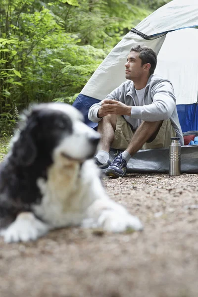 Man med hund sitter av tält — Stockfoto