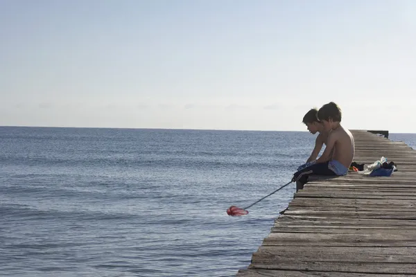 Boys sitting on jetty — Stock Photo, Image