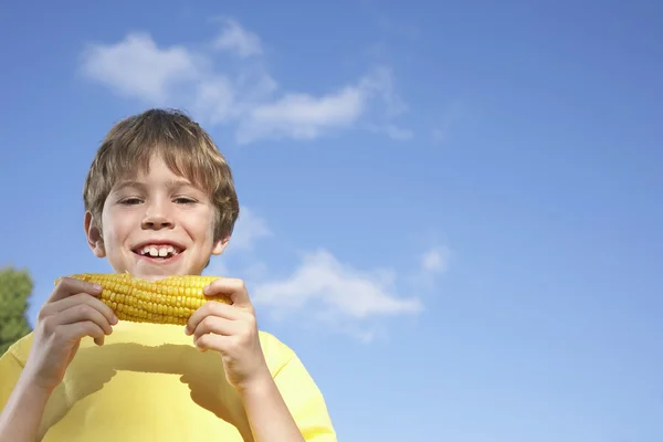 Мальчик ест кукурузу — стоковое фото