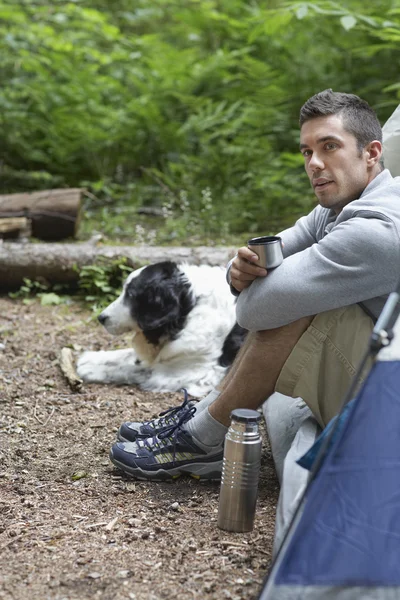 Человек с собакой сидит в палатке — стоковое фото