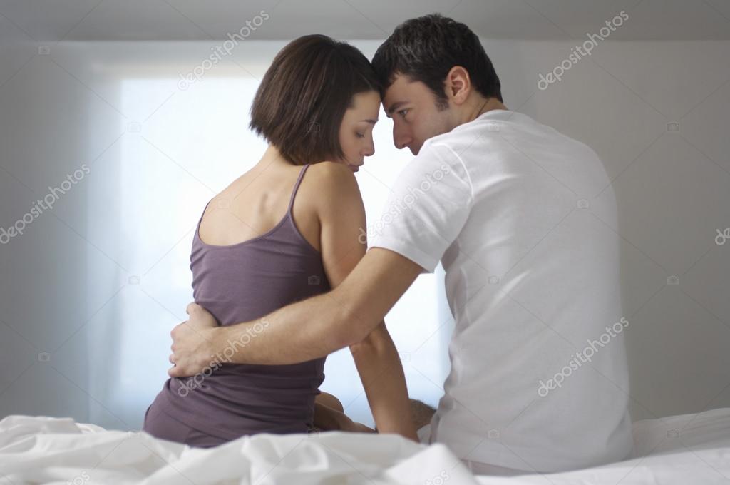Couple embracing sitting on bed