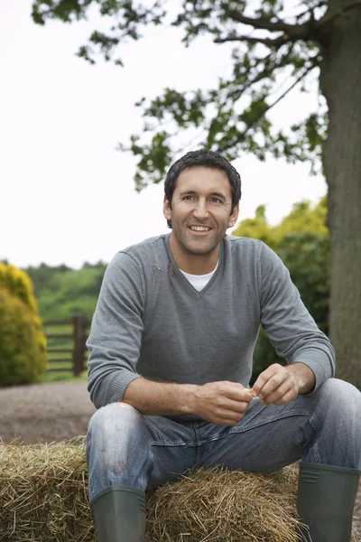 Man Sitting on Bail of Hay — Stock Photo, Image