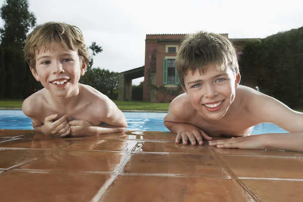 Boys leaning on edge of pool — Stock Photo, Image