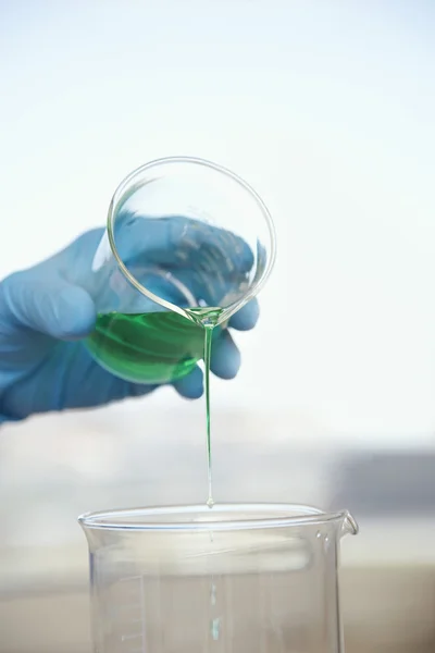 Cientista derramando líquido em copo — Fotografia de Stock
