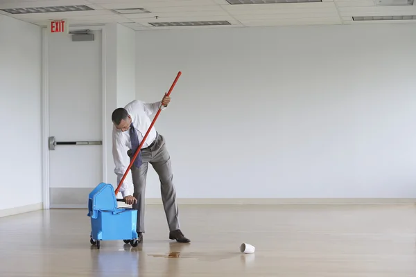 Empresario usando fregona en habitación vacía — Foto de Stock