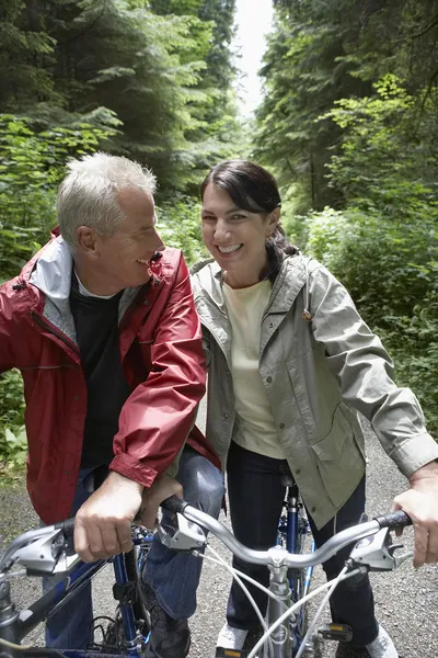 Man and middle-aged woman riding bikes — Stock Photo, Image