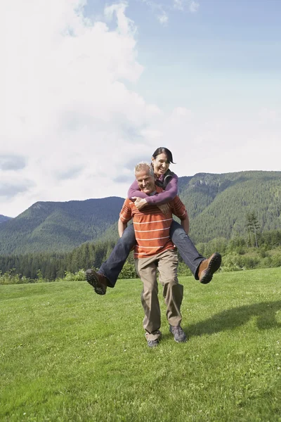 Man carrying woman piggy back — Stock Photo, Image