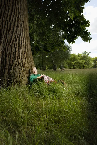 Kvinna sitter under ett träd — Stockfoto