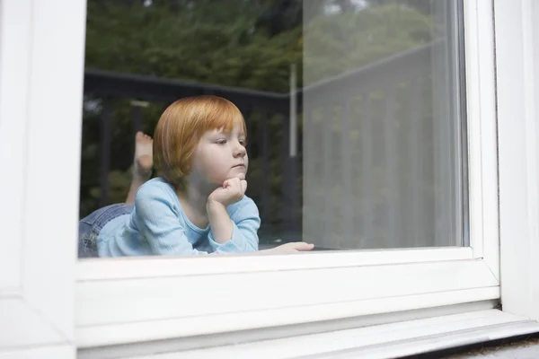 Girl looking through window — Stock Photo, Image