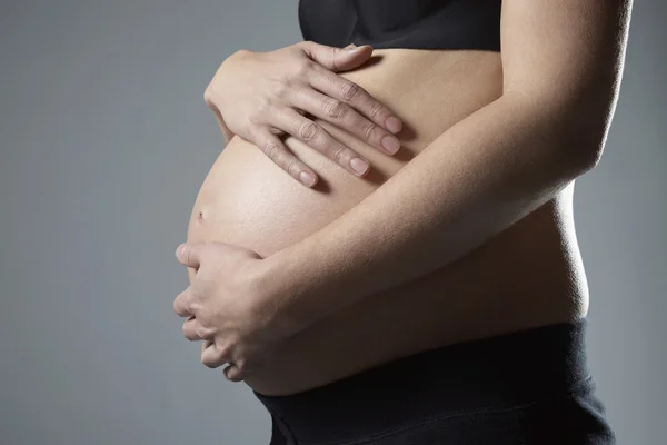 怀孕的女人控股腹部 — 图库照片