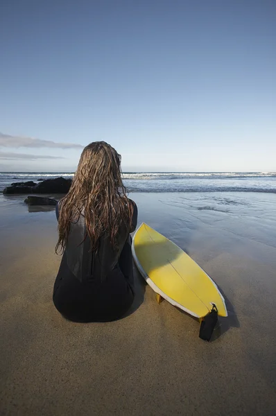 Kobieta siedzi przez desek surfingowych — Zdjęcie stockowe