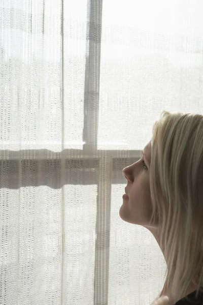 Woman looking through window — Stock Photo, Image