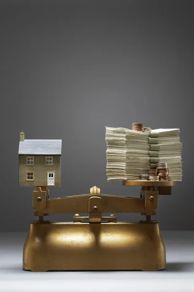 Modelo de casa y dinero en balanzas — Foto de Stock