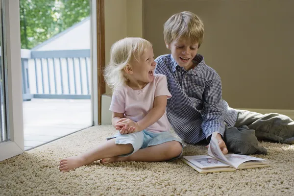 Frères et sœurs assis sur le tapis avec le livre — Photo