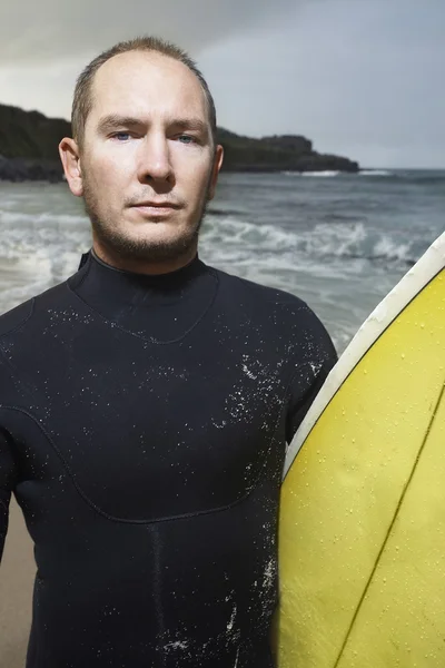 Hombre sosteniendo tabla de surf en la playa —  Fotos de Stock