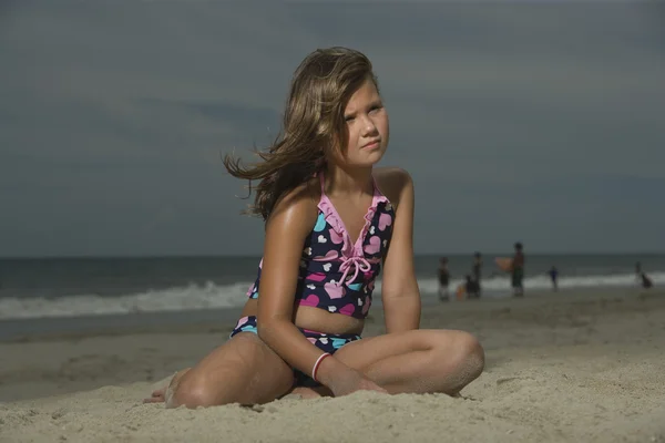 Chica sentada en una playa — Foto de Stock