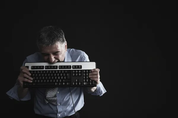 Bilgisayar klavyesindeki ısırma işadamı — Stok fotoğraf