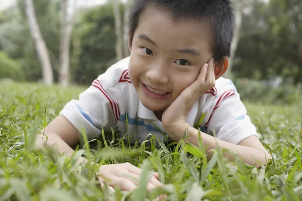 Jongen liggen op gras — Stockfoto