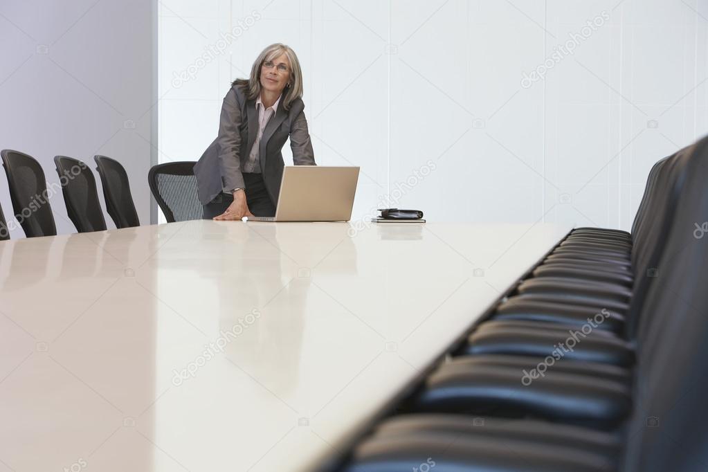 Businesswoman looking up by laptop in board room