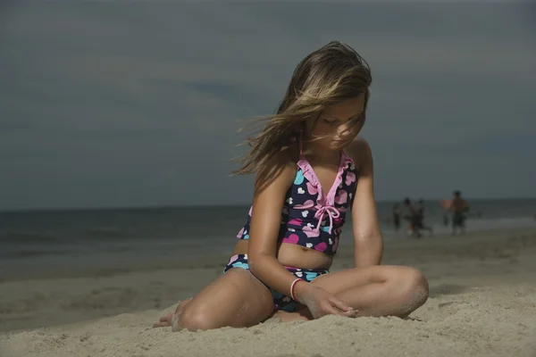Chica sentada en una playa — Foto de Stock