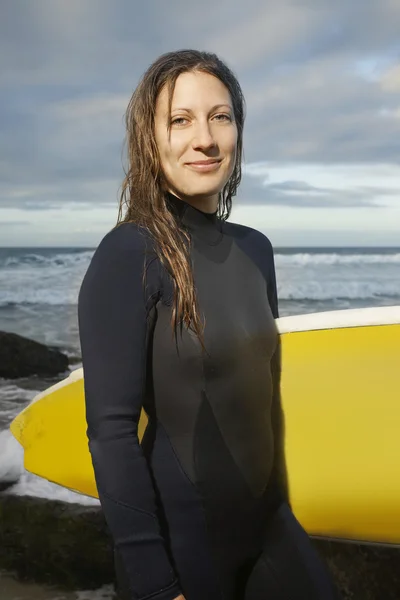 Surfista sosteniendo tabla de surf en la playa —  Fotos de Stock