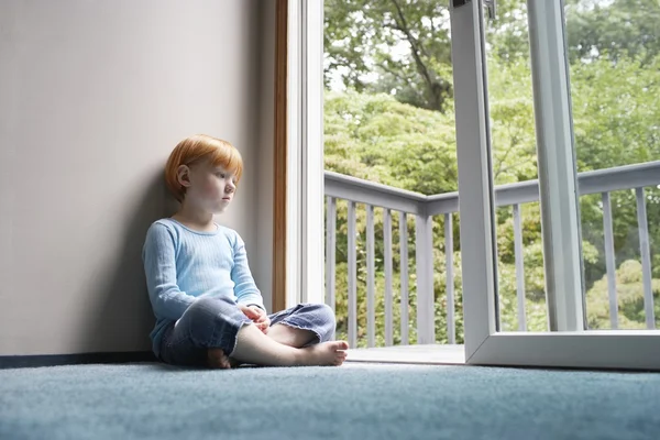 Little girl looking through balcony door — Stock Photo, Image