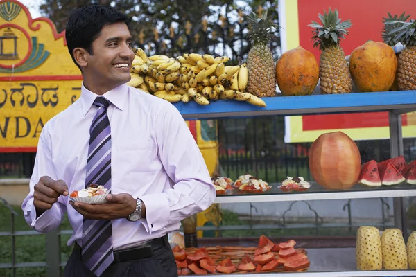 Businessman standing in front of fruit stall — Stock Photo, Image