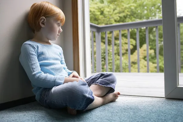 Girl looking through balcony door — Stock Photo, Image