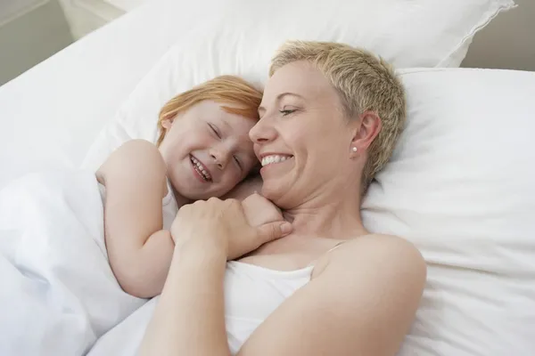 Mamma allomfattande dotter i sängen — Stockfoto