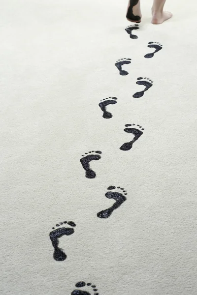 Woman leaving black footprints on carpet — Stock Photo, Image