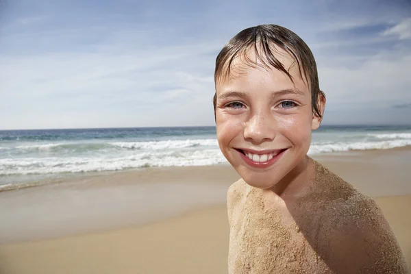 Boy covered with sand smiling