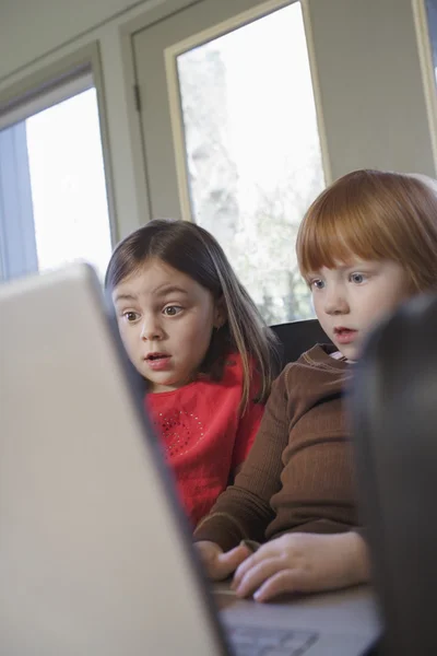 Pequeñas chicas sorprendidas utilizando el ordenador portátil — Foto de Stock