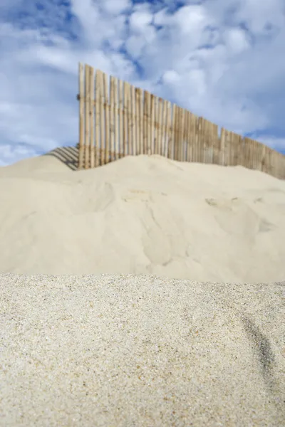 Wooden fence on sand dune — Stock Photo, Image