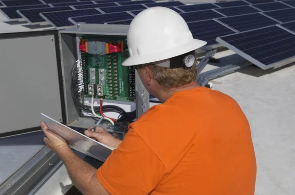 Elektrotechniker schreibt Notizen während er Stromkasten analysiert — Stockfoto