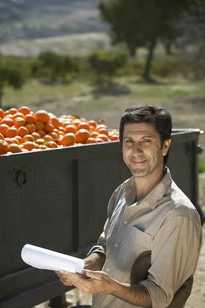 Agriculteur debout par camion avec des oranges — Photo